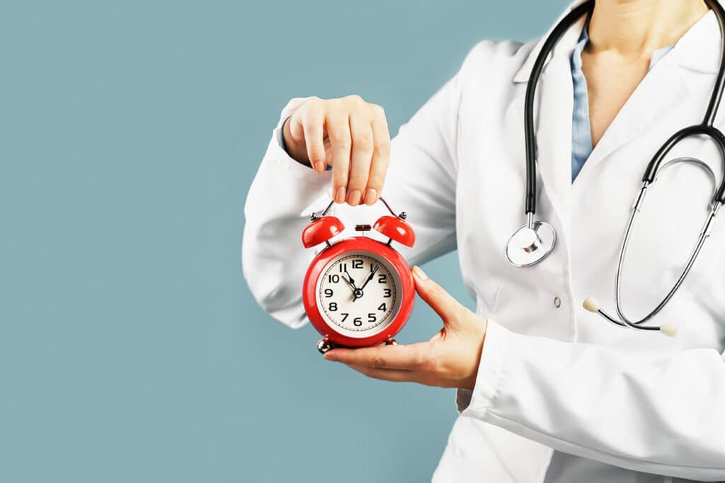 A medical professional holding an alarm clock.